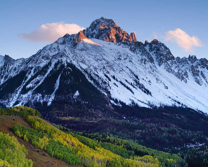 Mount Sneffels receives the last rays of warmth above fall colors in the valley below.