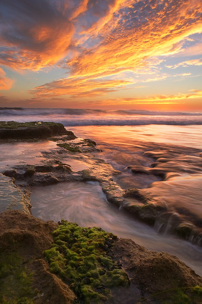 The last light of the day ignites the clouds above Swamis along the coast of San Diego.
