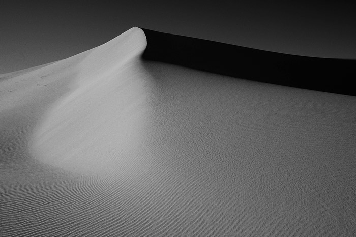 Early morning light casts a shadow across these sand dunes in Death Valley.