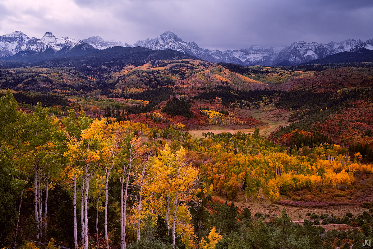 The soft light beneath the cloud cover of an approaching storm intensifies the autumn color of this aspen filled valley beneath...