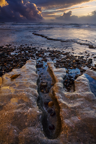 The last light of the day brings a gold tone to the foreground rocks and to an approaching storm.
