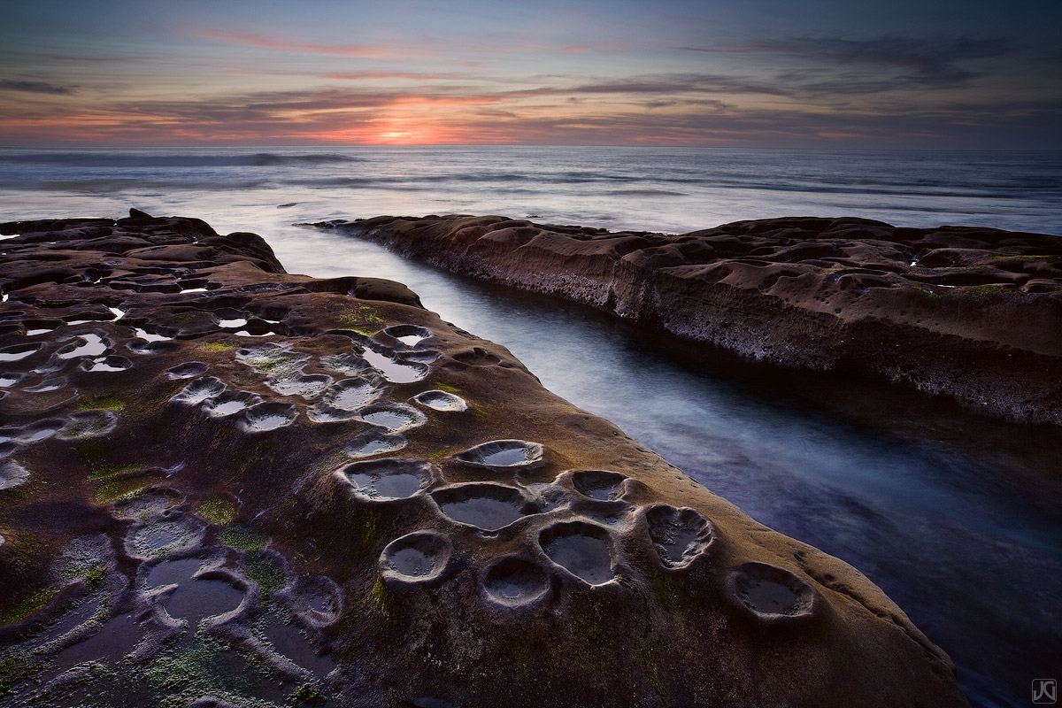 Unique rock formations along this San Diego stretch of scenic coast reflect the sunset sky above, while the tide rushes in and...