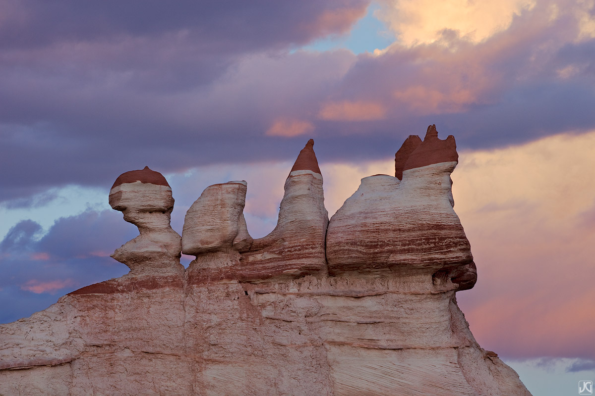 Sunset light paints the clouds pink behind this fragile sandstone formation in Arizona.&nbsp;