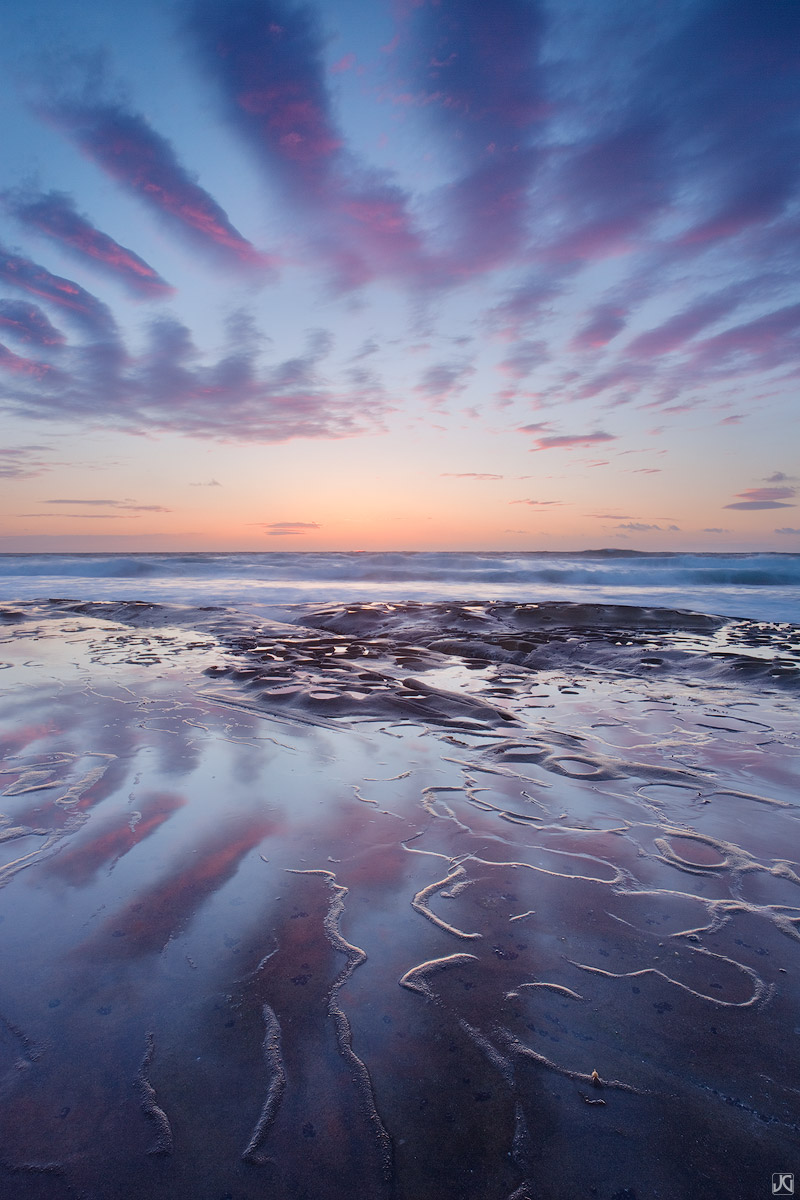 Sunset lights up these cloud fingers in the sky and reflections on this unique beach in San Diego County.