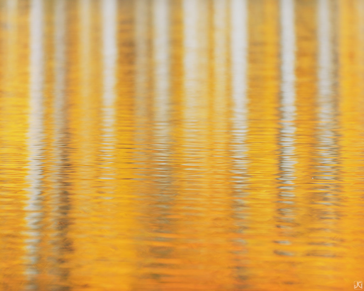 The vibrant colors of the aspen trees across the lake are visible in the reflections of this lake in the San Juan Mountains.