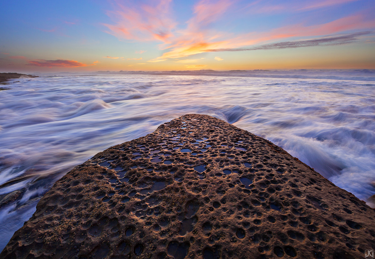 Incoming tidewater creates a blanket that this rock seems to be floating on top of at sunset.