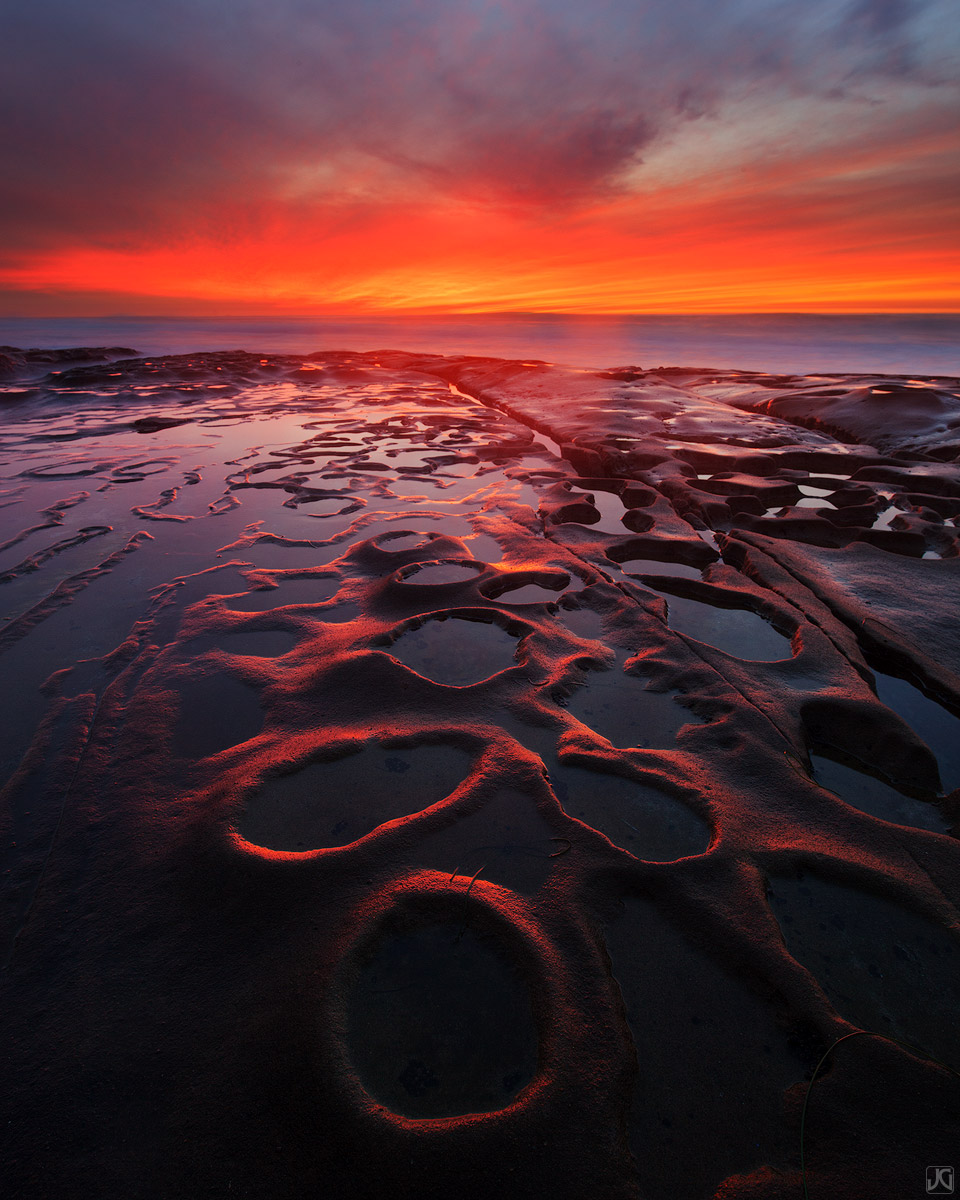 A nice sunset lights up the clouds and the potholes along the coast of San Diego.