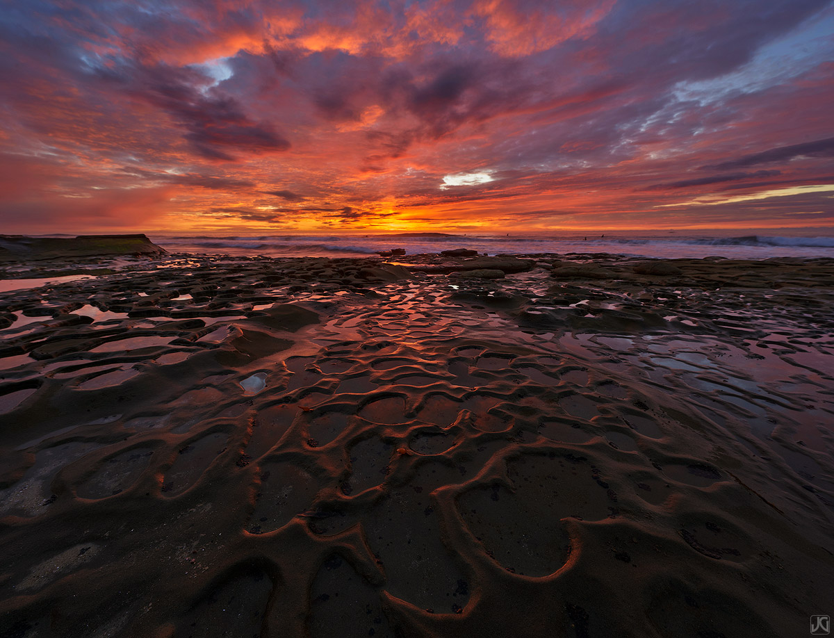 An explosion of color from an incredible sunset is reflected on the coast. These small pools or "potholes" often have a variety...