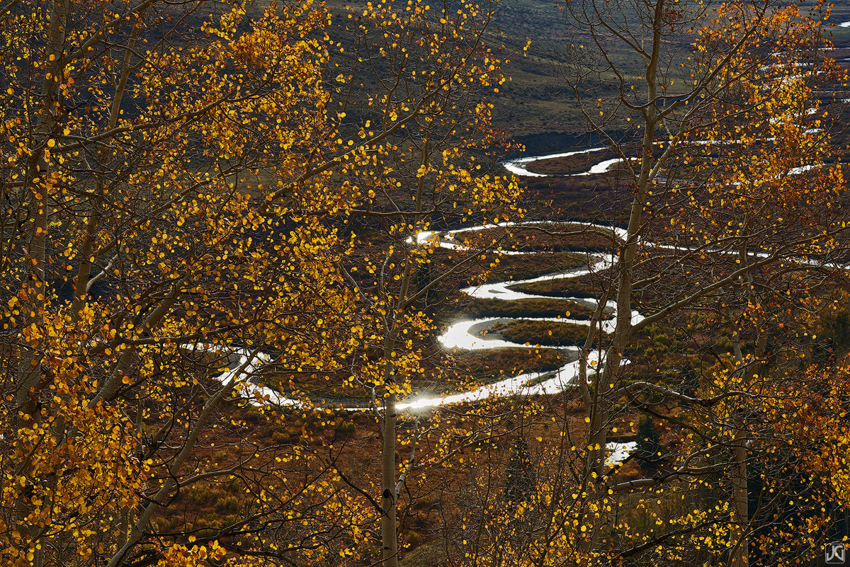 Winding through the valley, the East River reflects the sunhine, while the aspen glow on a calm, autumn morning.