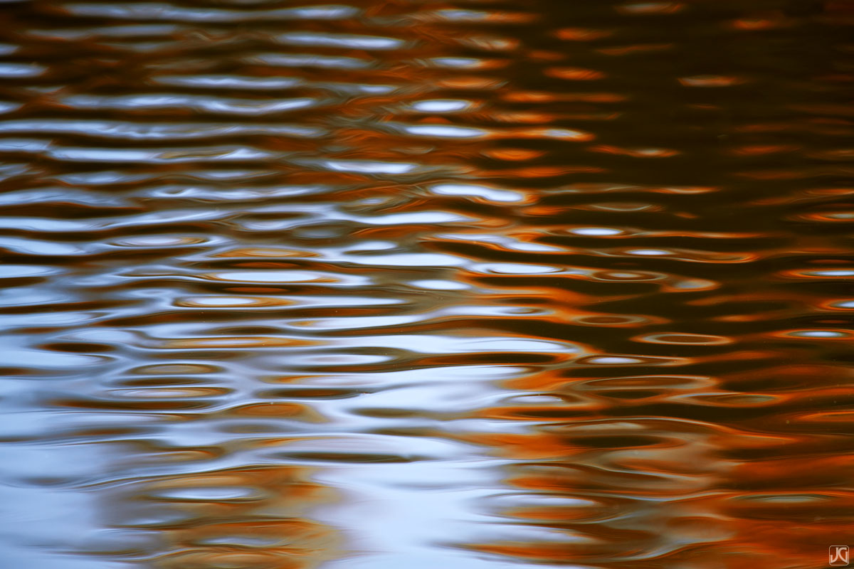Ripples flow across a small pond, creating an every changing exchange of autumn colors from nearby aspen trees and reflected...