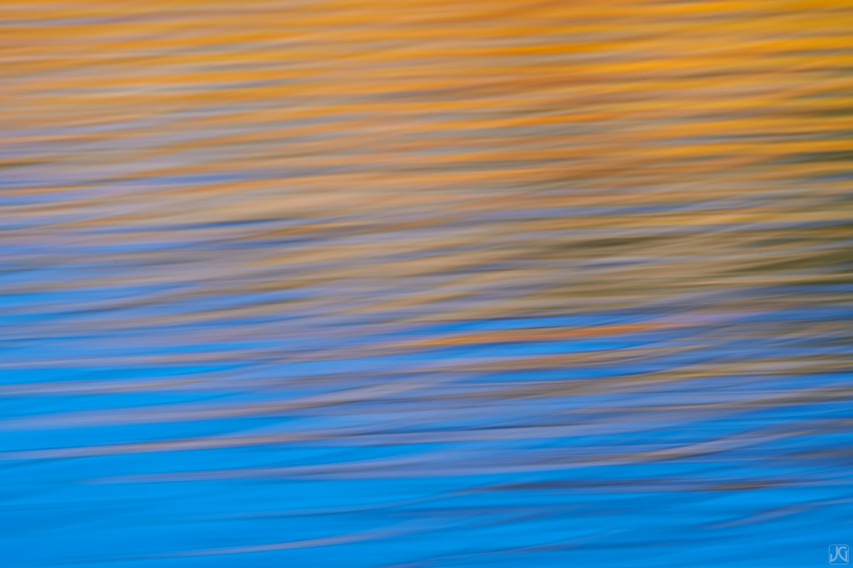 Autumn colors from nearby aspen trees combine with the reflections of the sky above.