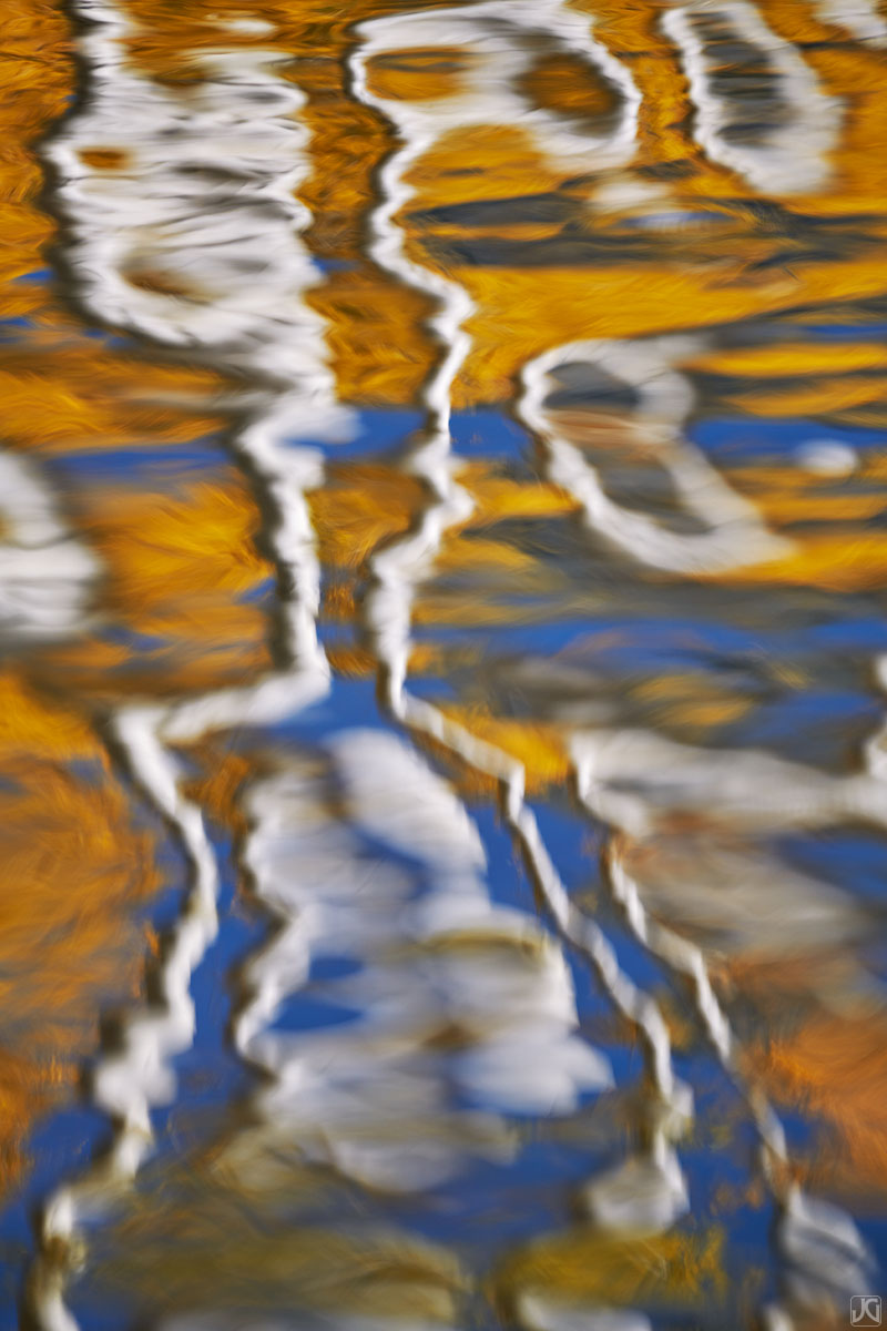 Aspen trees and autumn reflections dance on the surface of a lake.