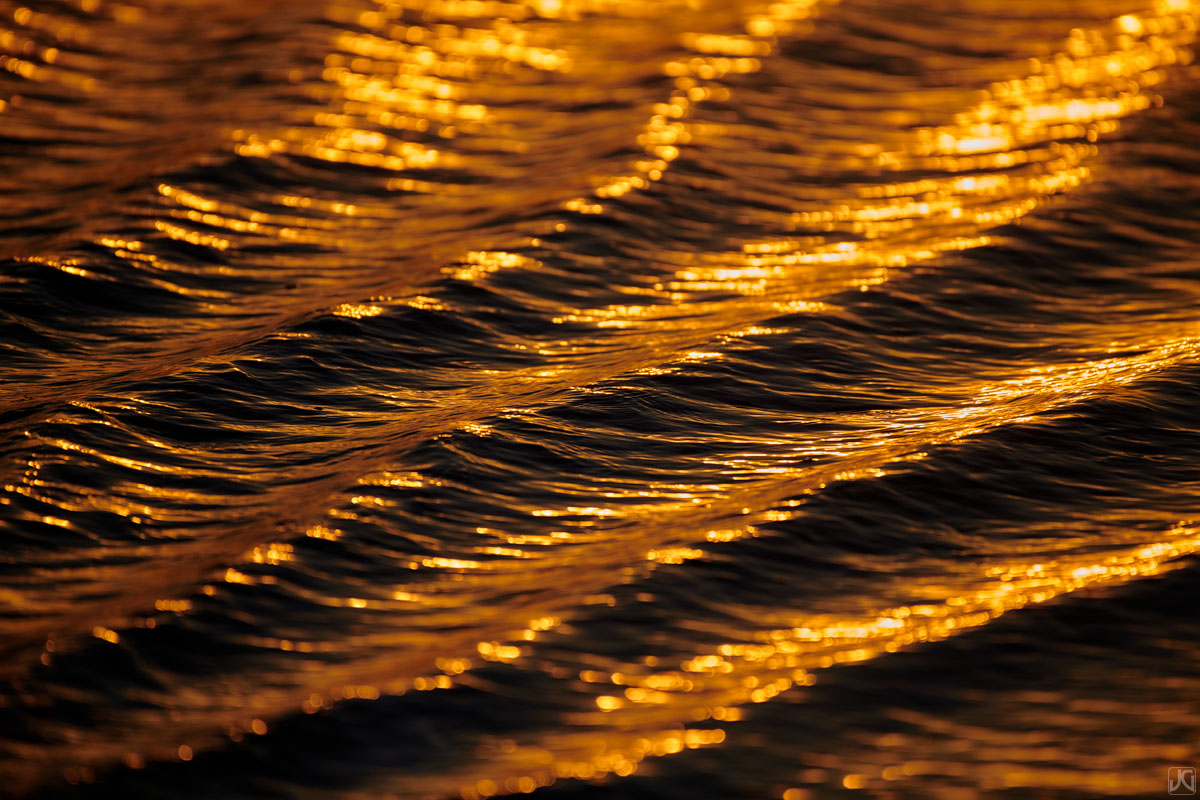 Sunset along the coast casts a golden hue upon these ripples.
