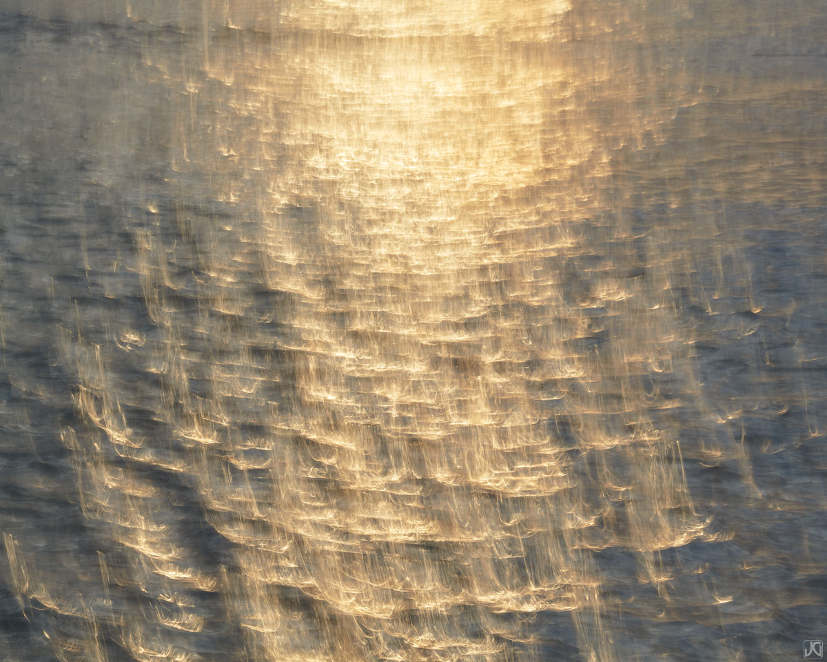 Gold colored light at sunset is painted across the ocean canvas.